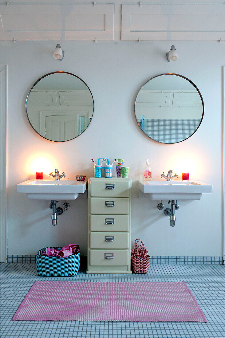 Circular mirrors hang above double wash basins in Odense bathroom