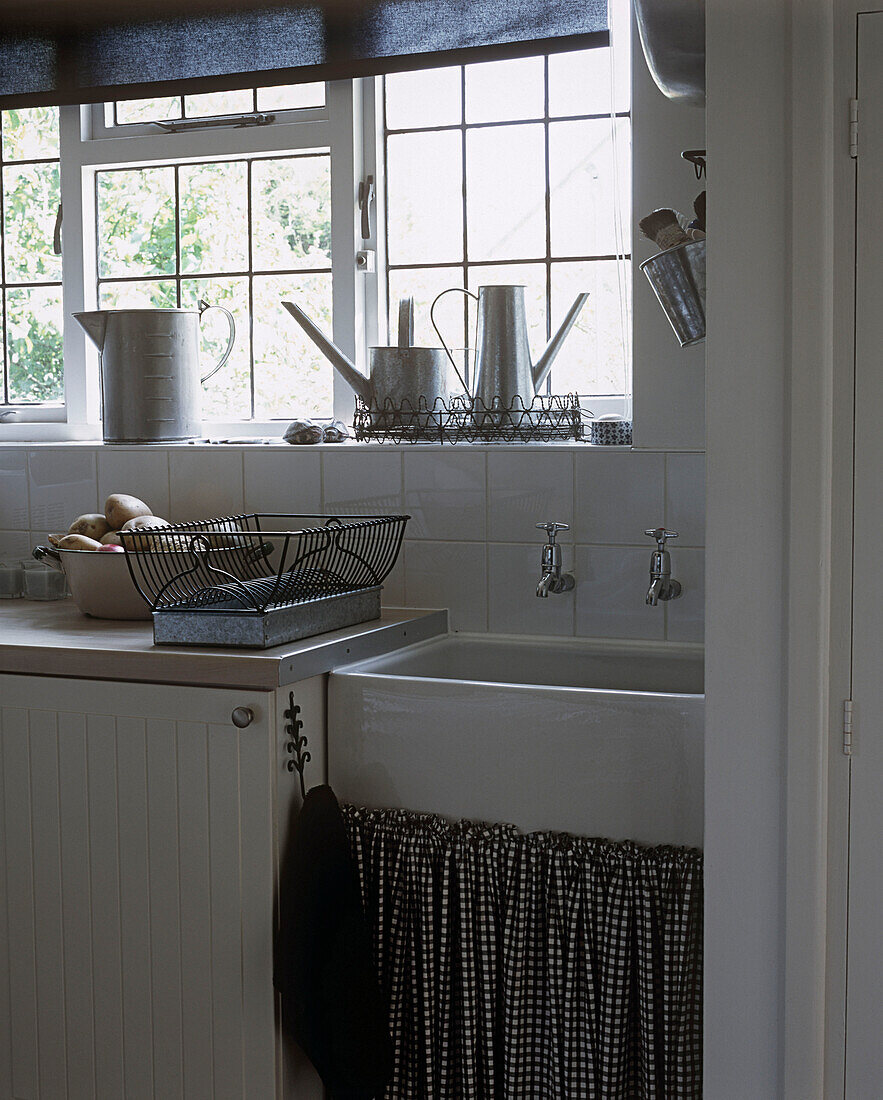 Kitchen sink with watering cans on window sill