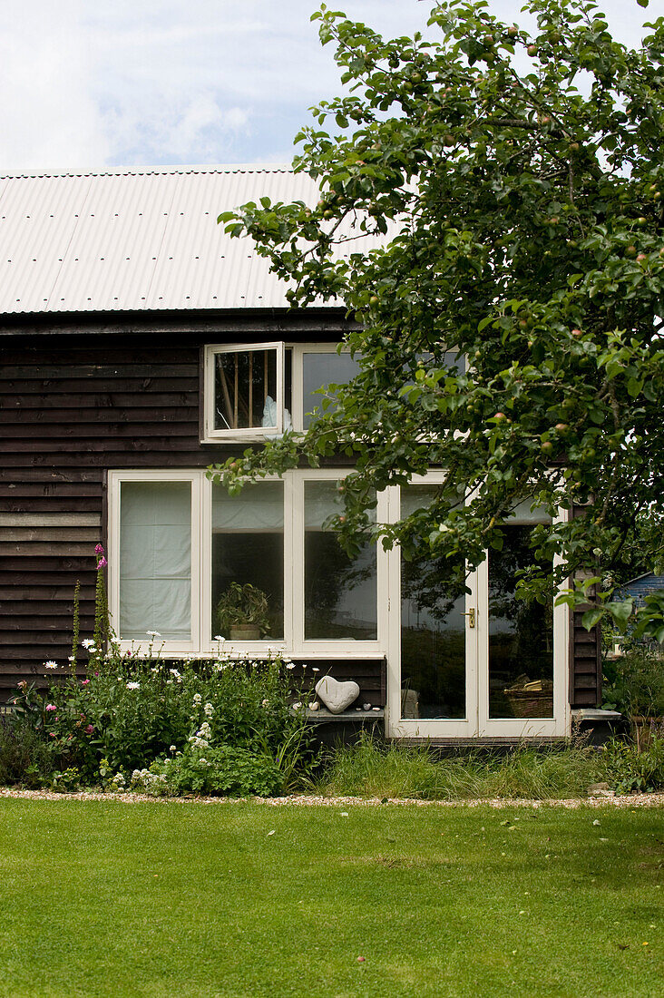 Außenansicht eines Hauses mit Holzverschalung in einem grünen Garten