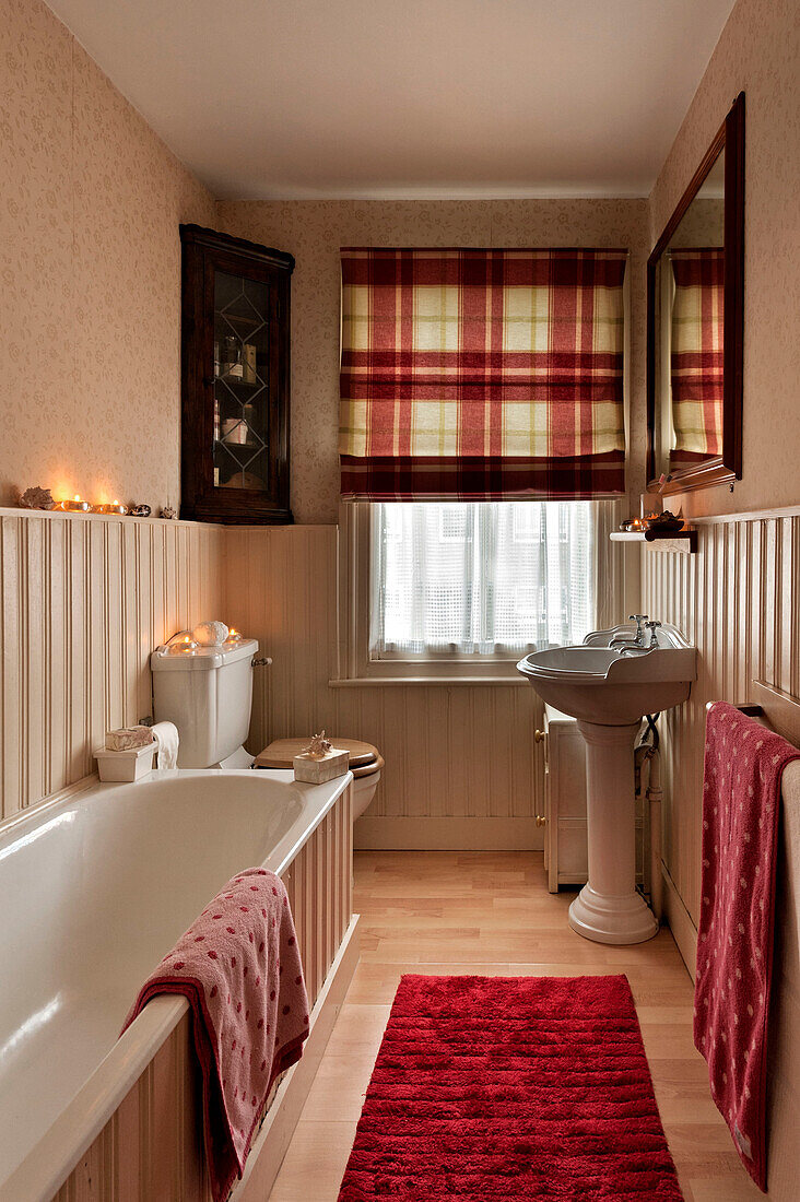 Gepunktete Handtücher mit karierten Raffrollos im Badezimmer eines Hauses in London UK