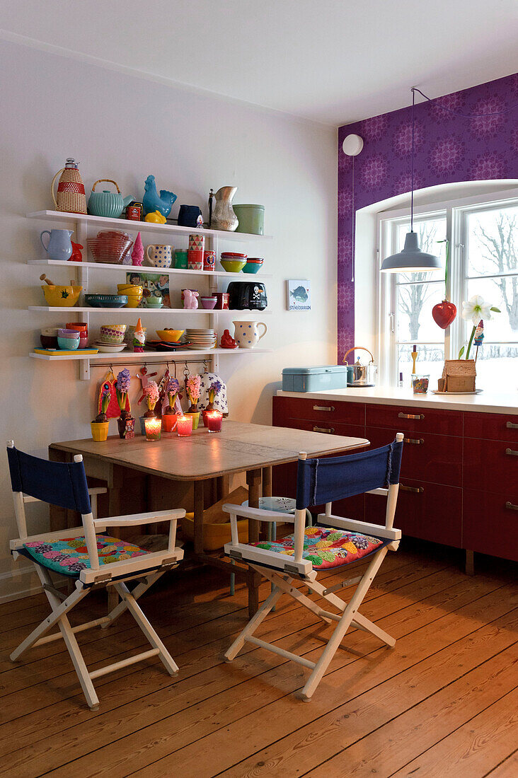 Directors chairs at table below kitchen sehlving in modern Odense family home Denmark