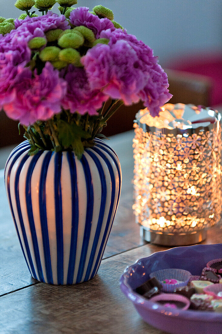Schnittblumen und brennende Kerze mit Petit Fours auf Tisch in modernem Familienhaus in Odense Dänemark