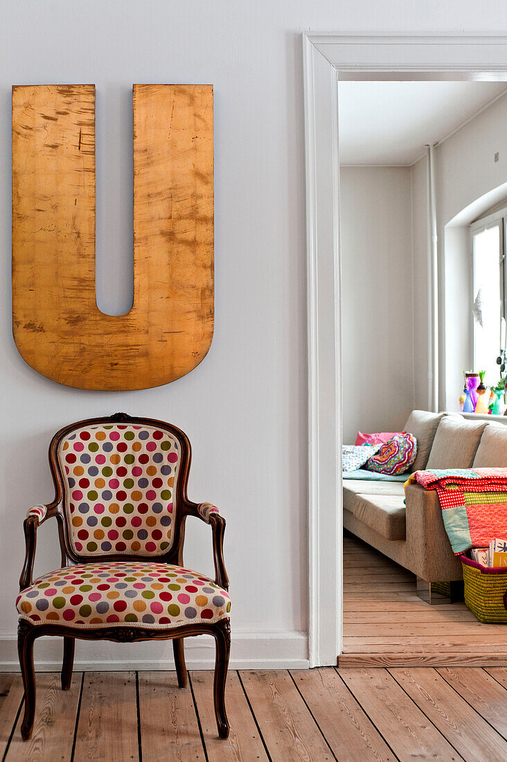 Upholstered amchair under oversized letter U in hallway of modern Odense family home Denmark