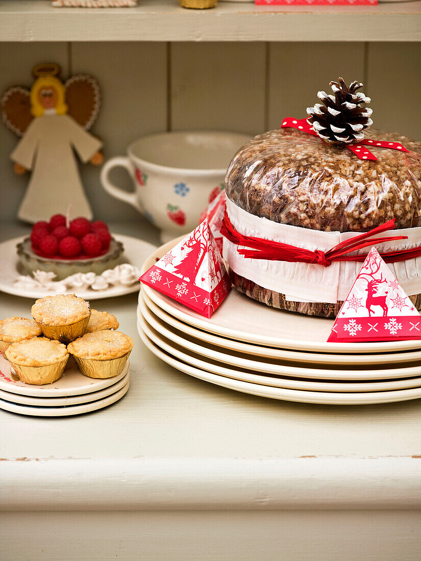 Weihnachtskuchen und Hackfleischpasteten mit Tellern auf der Küchenkommode
