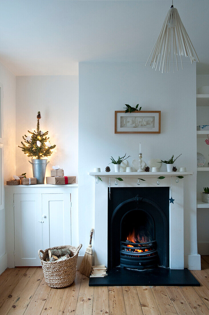 Gift wrapped presents under Christmas tree with original fireplace in Richmond-on-Thames London