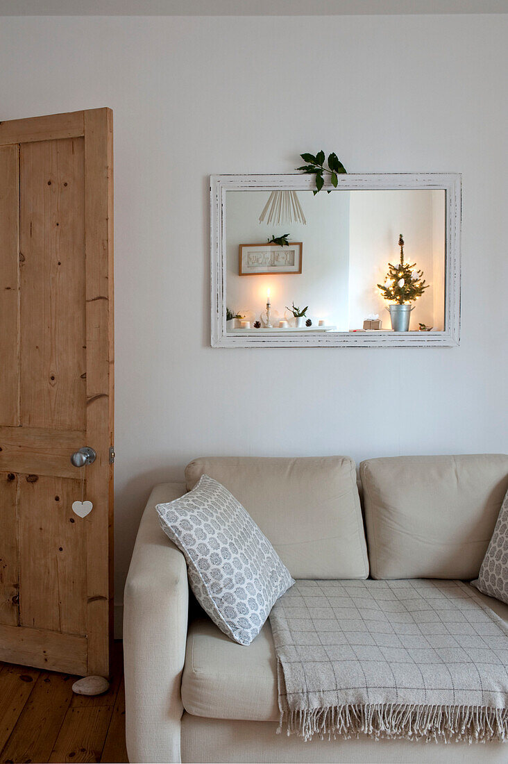 Rechteckiger Spiegel über cremefarbenem Sofa mit Holztür in einer Londoner Wohnung