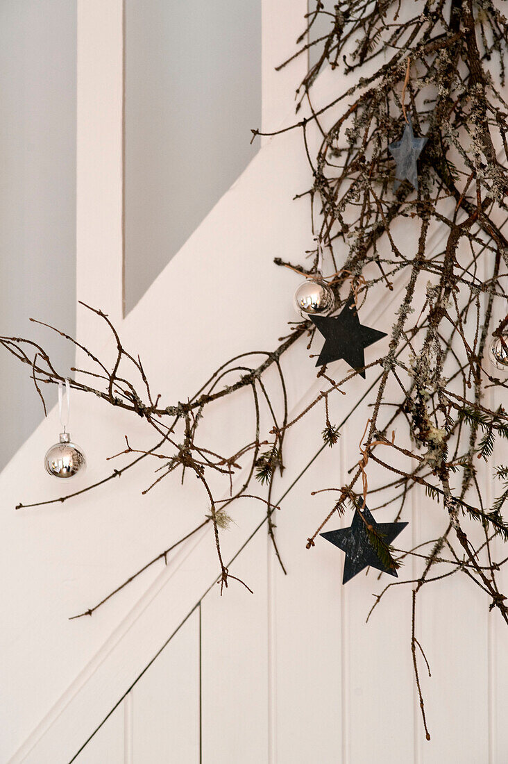 Silberne Kugeln und sternförmige Dekorationen an einem Kiefernzweig in einem Londoner Haus