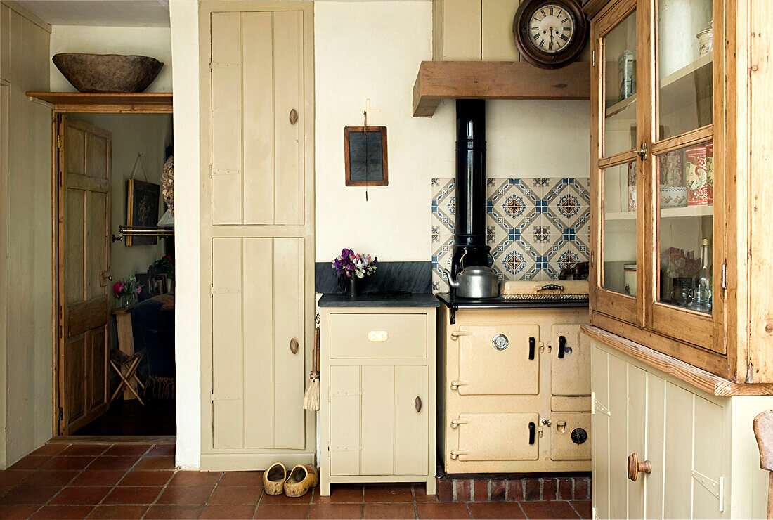 Devon-Küche mit eingebautem Stauraum und gemusterter Kachelrückwand über dem Herd