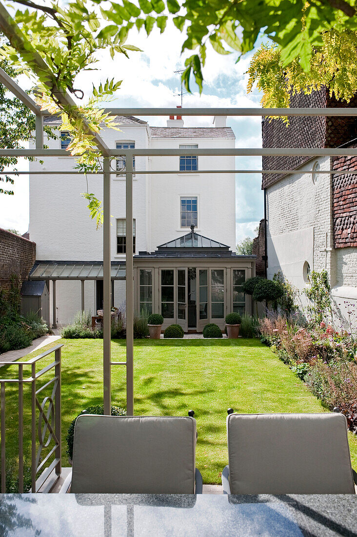 Lawned garden exterior of white London townhouse with conservatory extension England UK