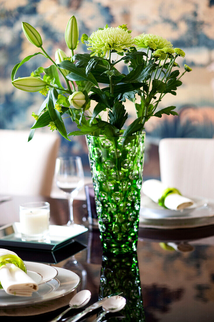 Chrysanthemen und Lilien in grüner Glasvase auf dem Esstisch in einem Stadthaus in West London England UK