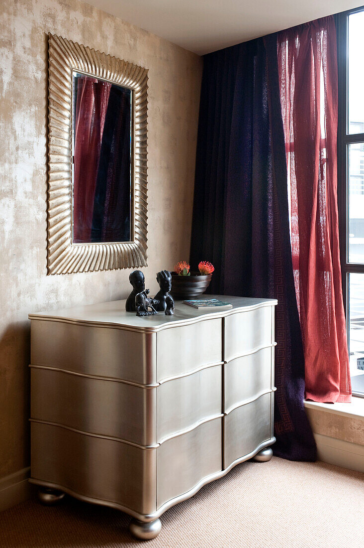 Goldgerahmter Spiegel über einer Metallkommode im Schlafzimmer einer Londoner Wohnung, England, UK