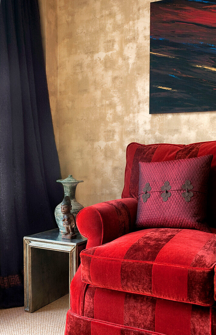 Triptychon über rot gestreiftem Sofa in goldfarbenem gedämpftem Metallic-Wohnzimmer in Londoner Wohnung England UK