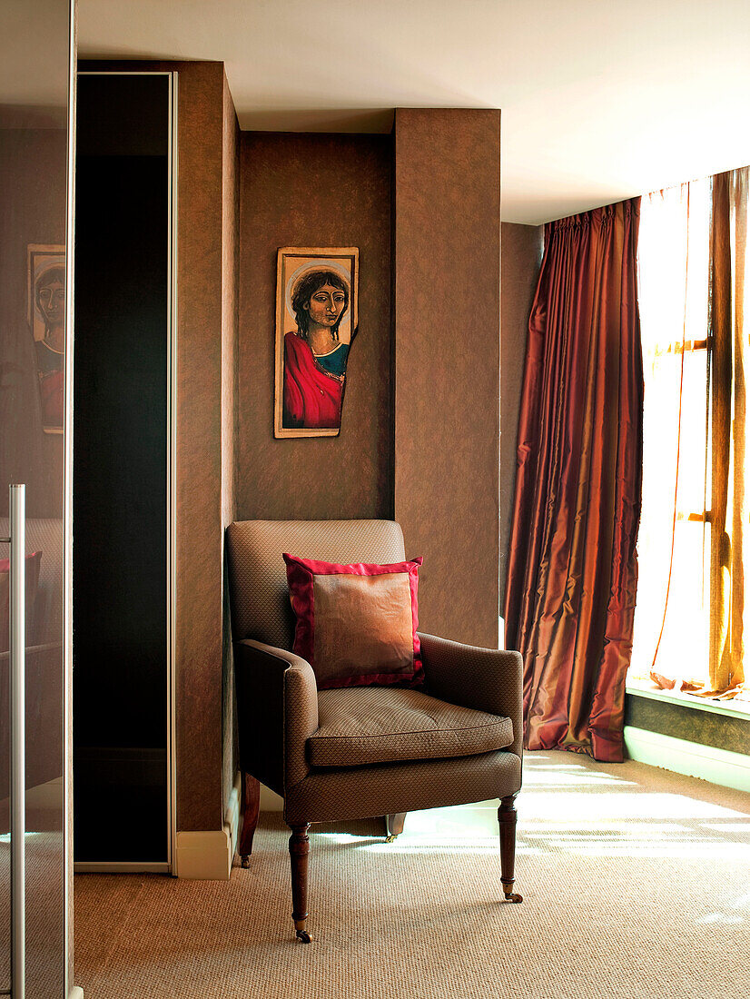 Armchair and artwork at doorway in London apartment England UK