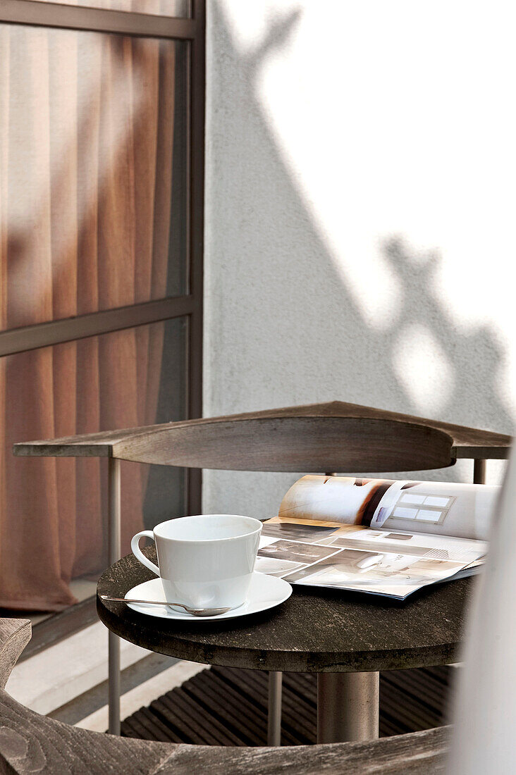 Cup and saucer with open magazine on table of balcony exterior London apartment England UK