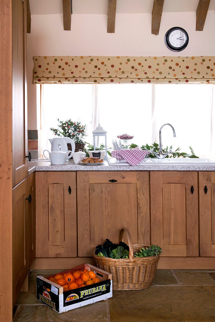 Basket and crate with wooden fitted sink units in rural Suffolk home England UK