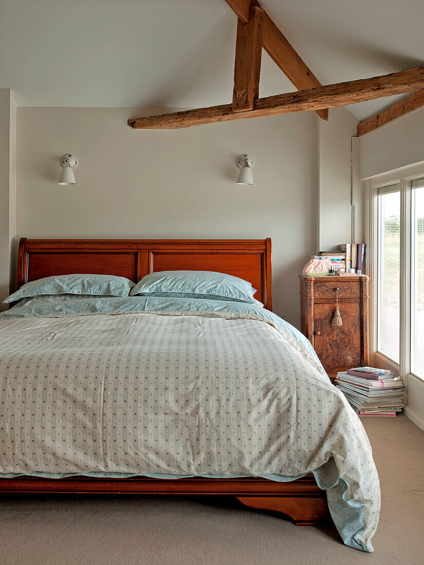 Doppelbett mit Schrank unter strukturellem Deckenbalken in einem Einfamilienhaus in Suffolk, England, UK