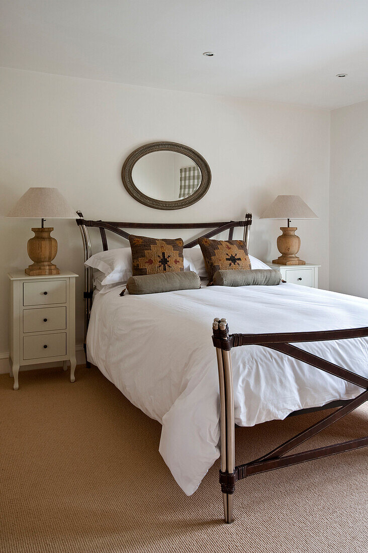 Ovaler Spiegel und passende Lampen über einem Bett mit Lederriemen in einem Haus in Canterbury England UK