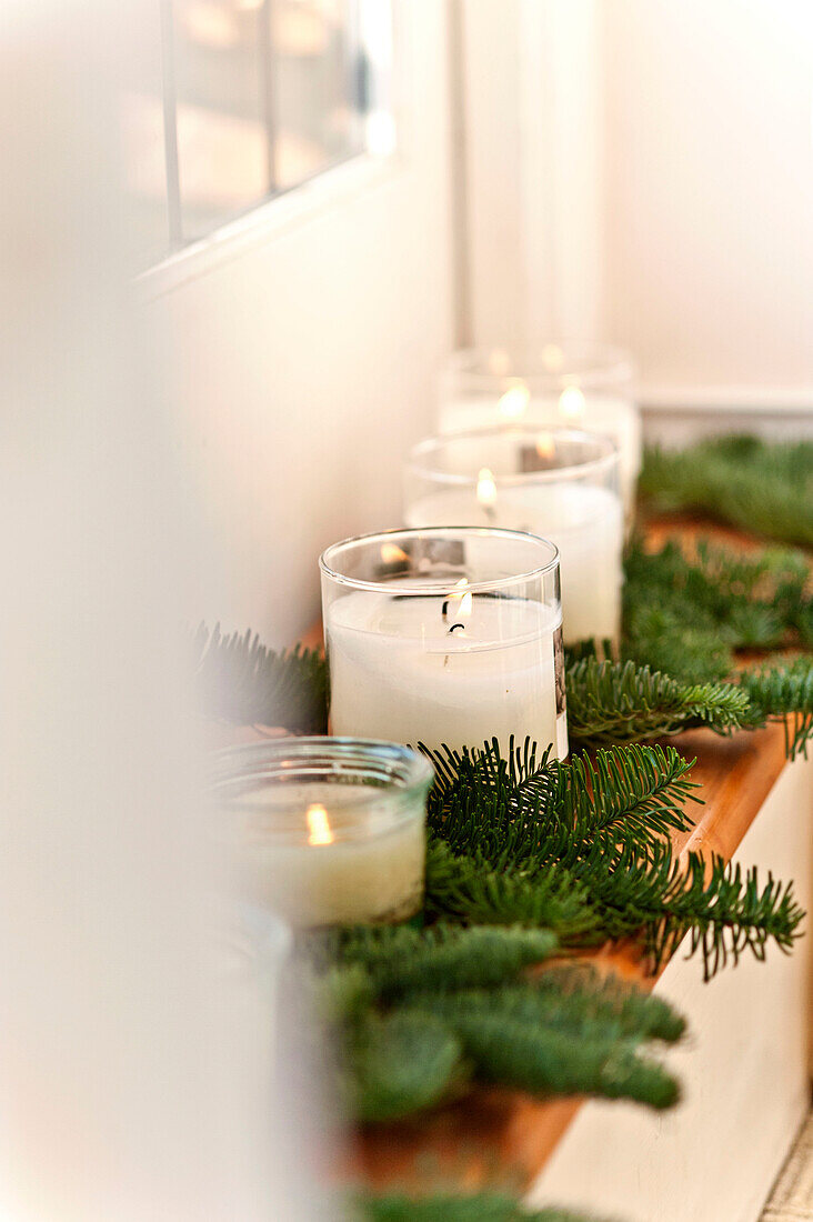 Lit candles and pine needles on shelf in Forest Row family home, Sussex, England, UK