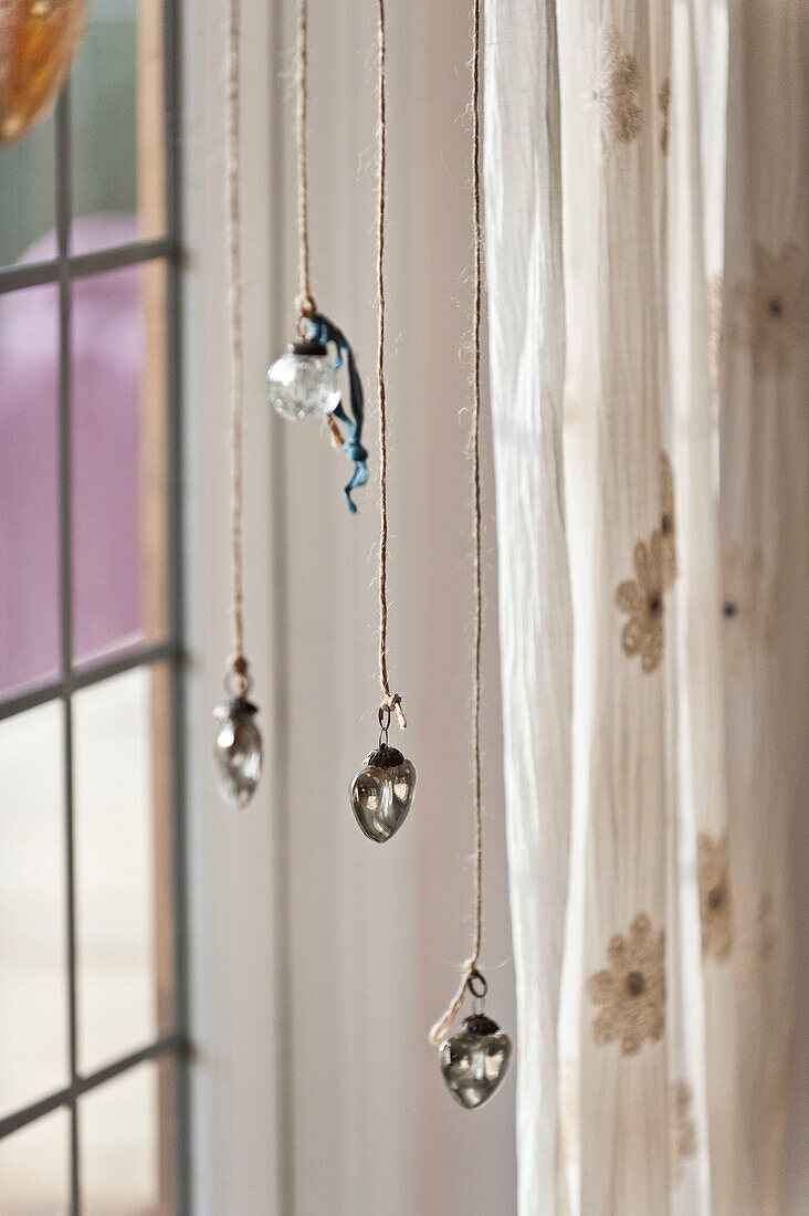 Vier Glaskugeln hängen im Fenster des Hauses der Familie Forest Row, Sussex, England, UK