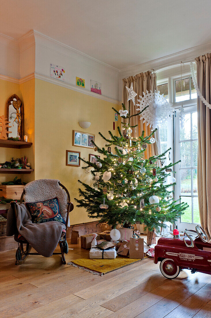 Geschenke und Spielzeugauto unter dem Weihnachtsbaum am Fenster des Hauses der Familie Forest Row, Sussex, England, Vereinigtes Königreich