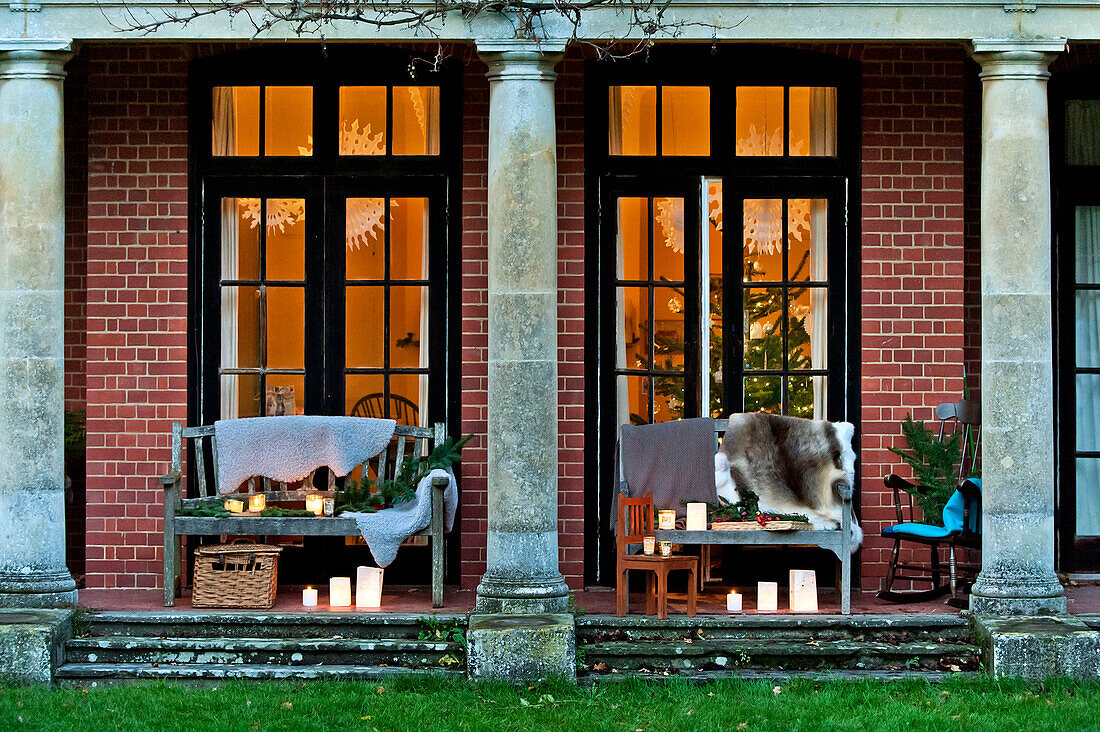 Fur throw on bench seats with lit candles, Forest Row family home, Sussex, England, UK