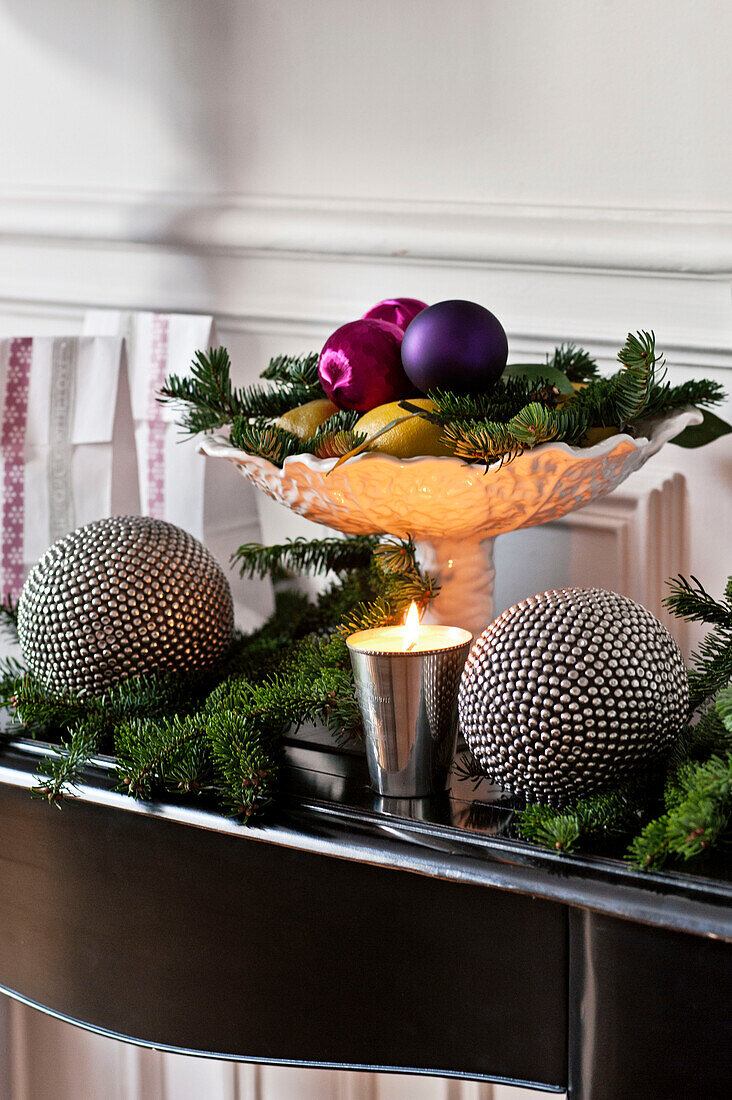 Lit candle and baubles with pine needles on sideboard in Paris apartment, France
