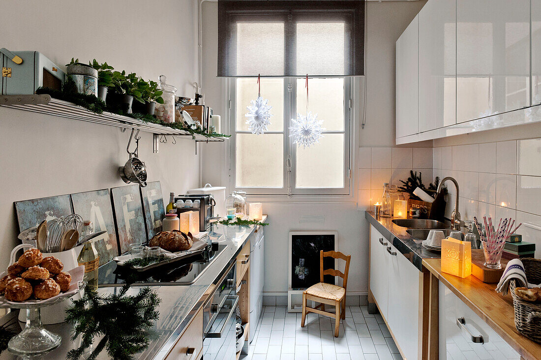 Festive greenery in white fitted kitchen of Paris apartment, France