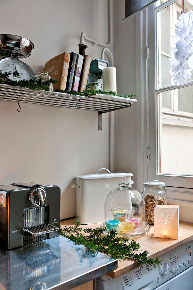 Rezeptbücher und Waage auf einem Regal über der Küchentheke mit Kaffeemaschine aus Edelstahl in einer Wohnung in Paris, Frankreich