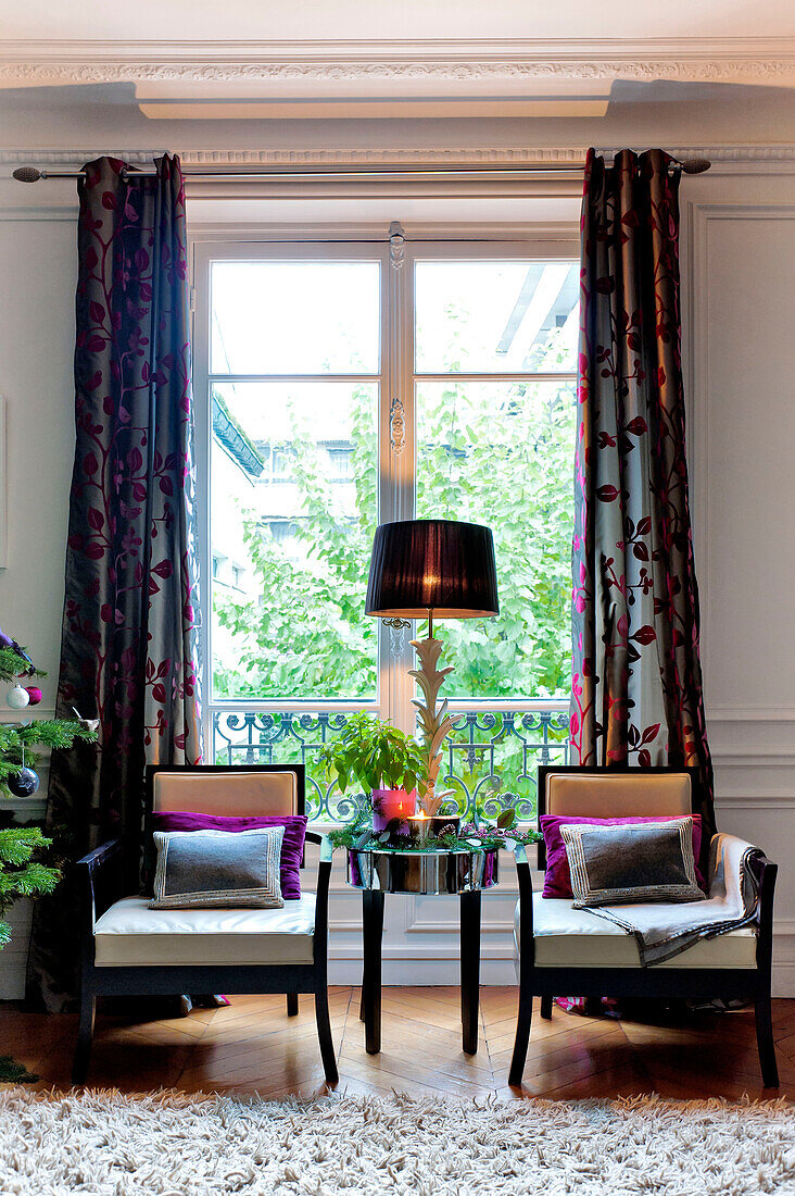 Pair of wooden armchairs at french doors in Paris apartment, France