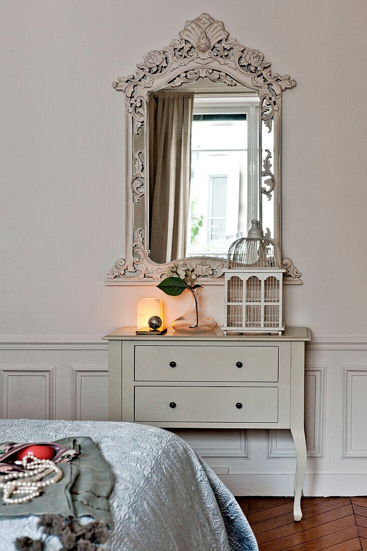 Dekorativer antiker Spiegel über einem einfachen Schubladenset im Schlafzimmer einer Wohnung in Paris, Frankreich