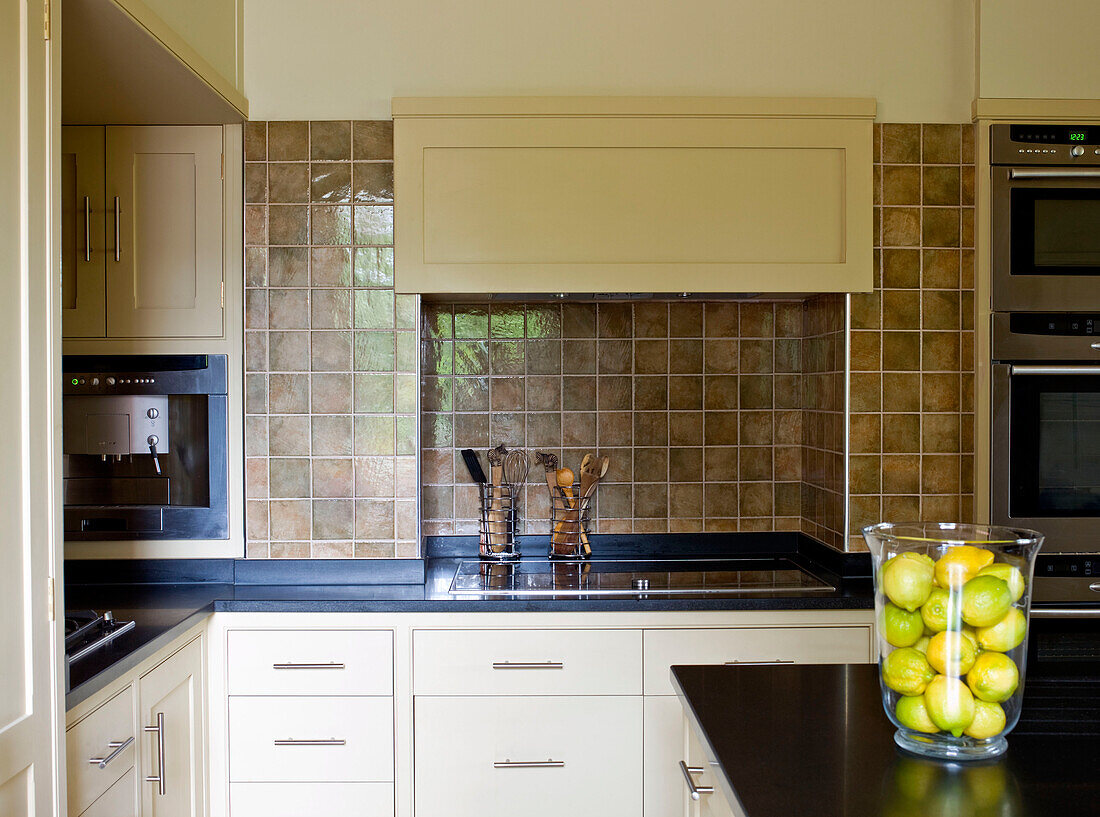 Vase mit Zitronen in braun gefliester Küche mit cremefarbenen Einbaugeräten in einem Haus im ländlichen Suffolk England UK