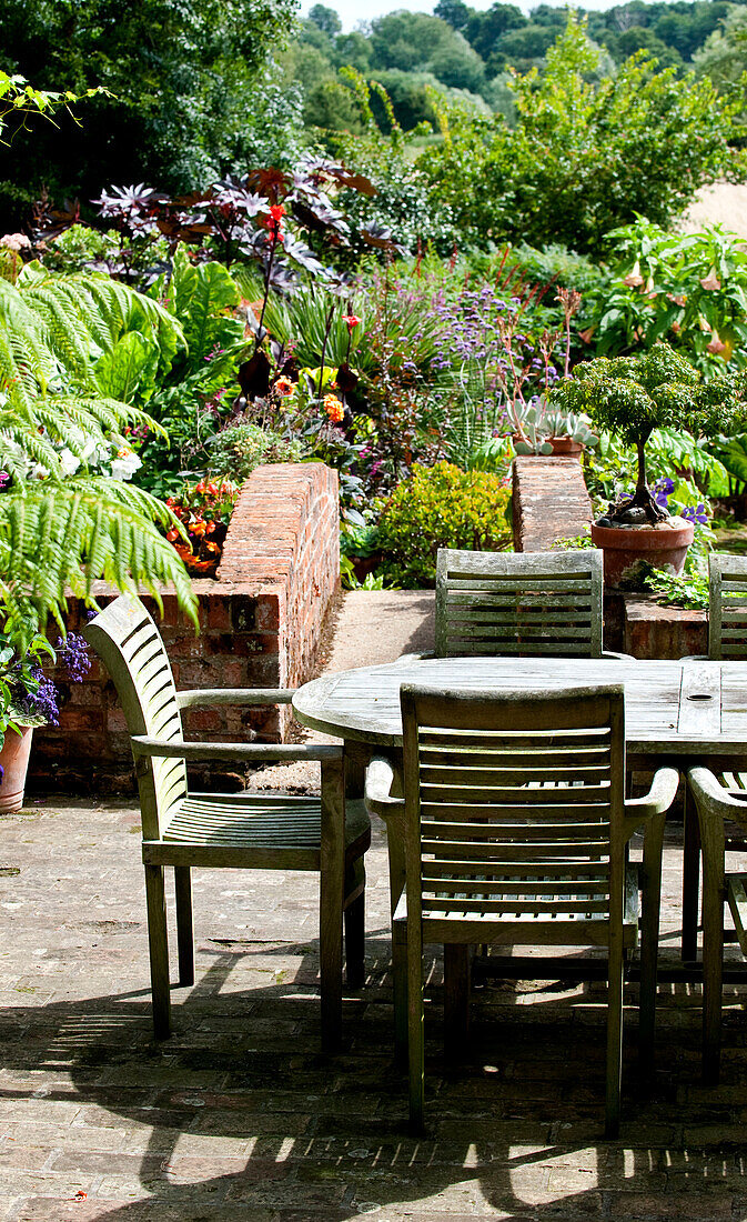 Garden table and chairs in rural garden exterior of Suffolk country house England UK