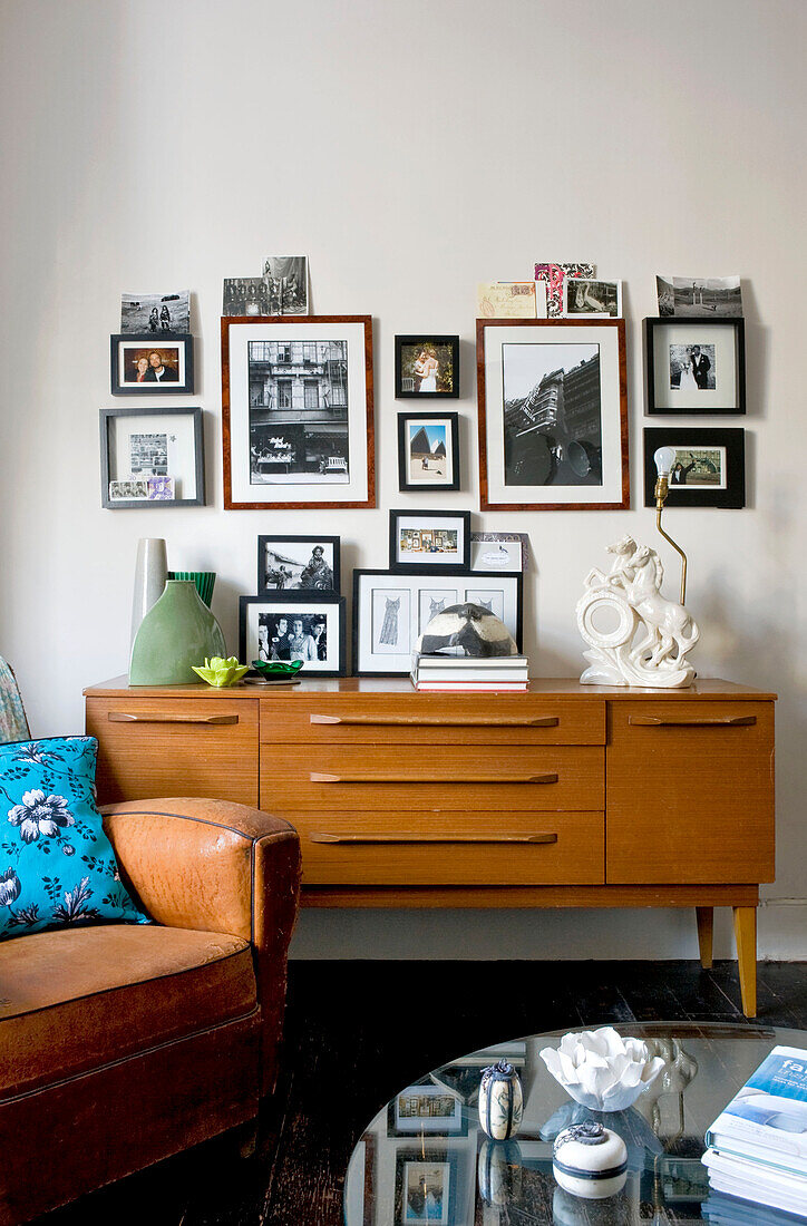 Artwork display above 1960s style wooden sideboard in London home, UK