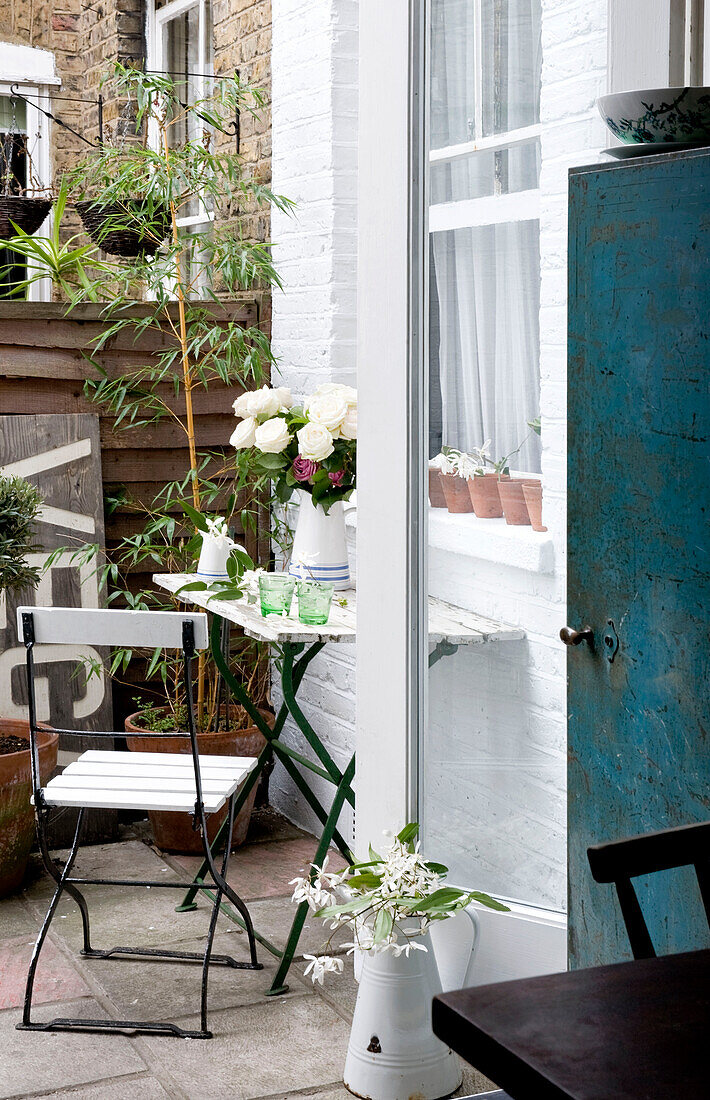 Blick durch die Hintertür auf einen Klappstuhl und einen Tisch im Hof eines Hauses in London, UK
