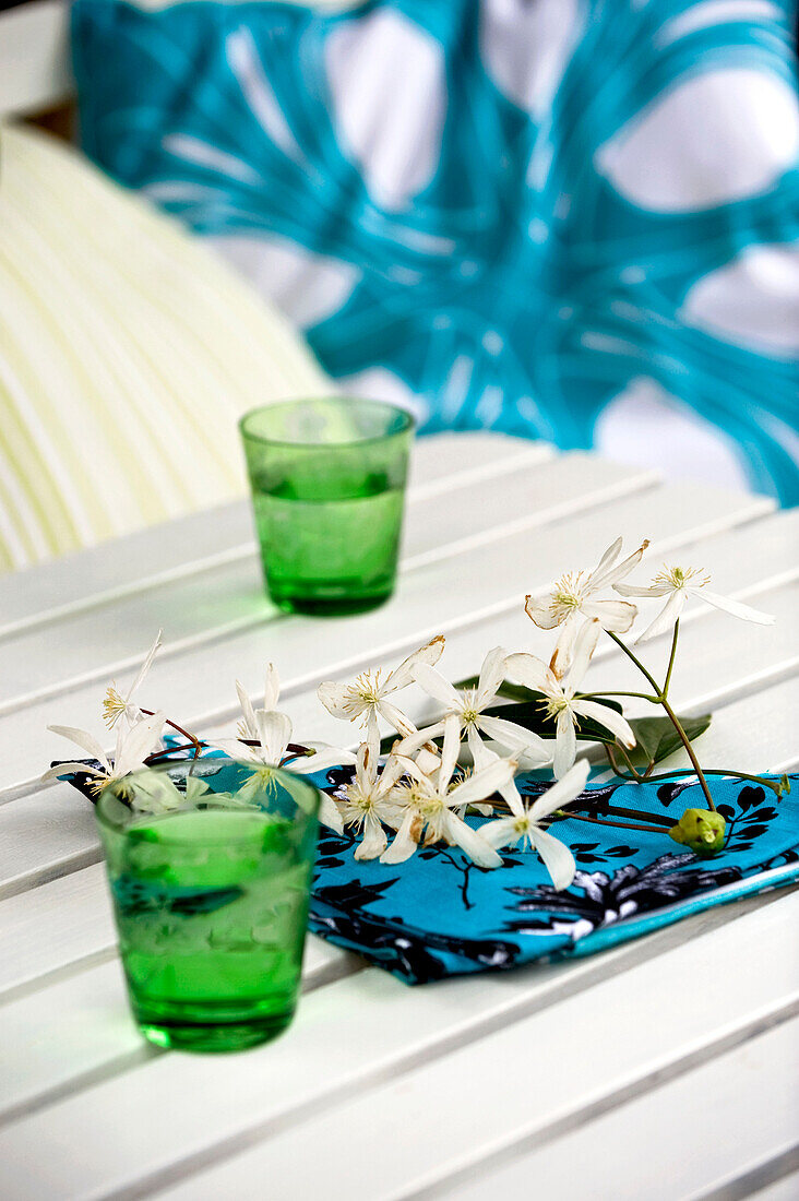 Blütenzweig auf Serviette am Tisch mit grünen Gläsern, London, UK