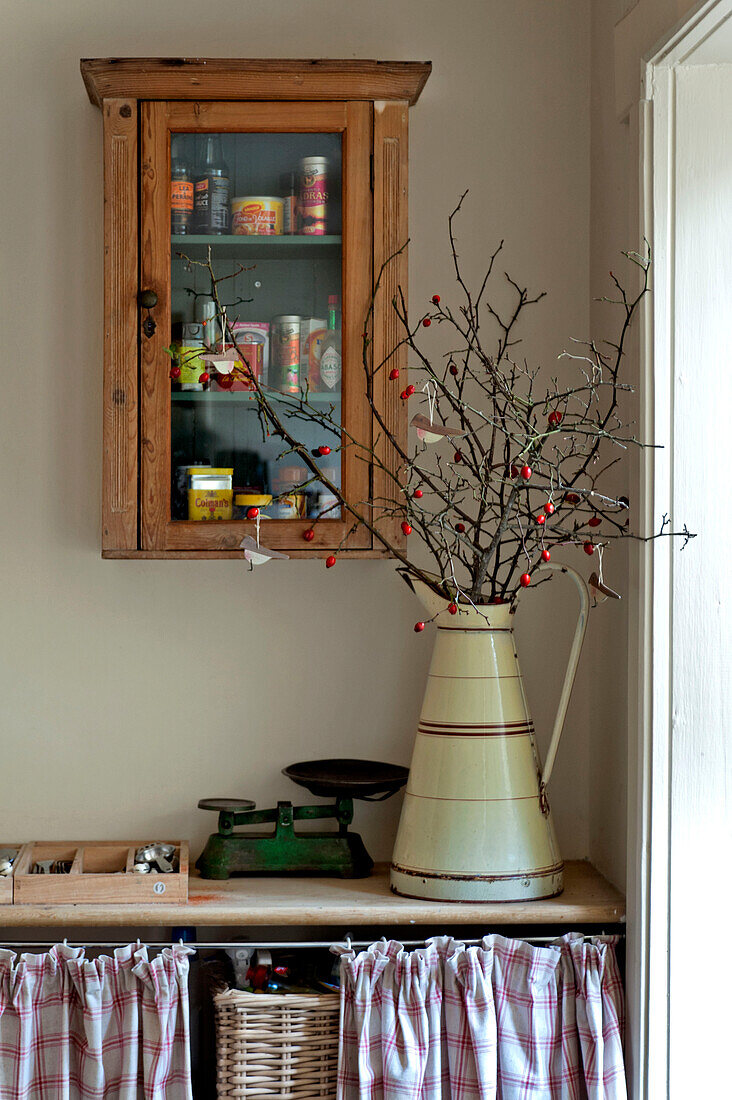 Glasschrank und Zweigarrangement in der Küche eines Hauses in Walberton, West Sussex, England, UK