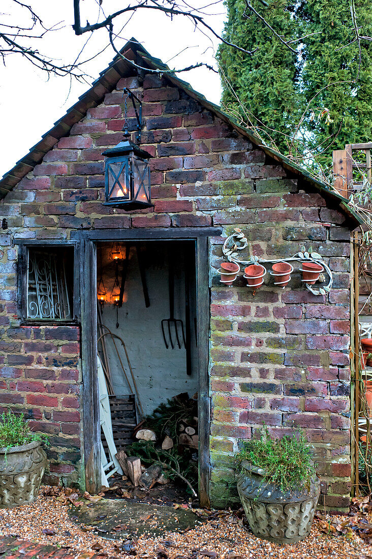 Lit lantern on brick wood shed in Walberton, West Sussex, England, UK