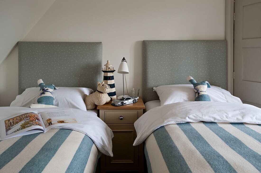 Gestreifte Bettdecken auf Einzelbetten mit Leuchtturm auf dem Tisch in einem Haus in Buckinghamshire, England, Vereinigtes Königreich