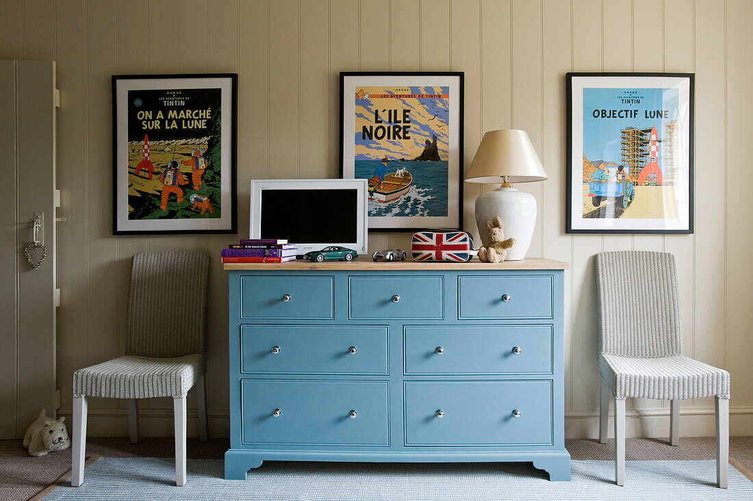 Turquoise sideboard with vintage prints and a pair of cane chairs in Buckinghamshire home, England, UK