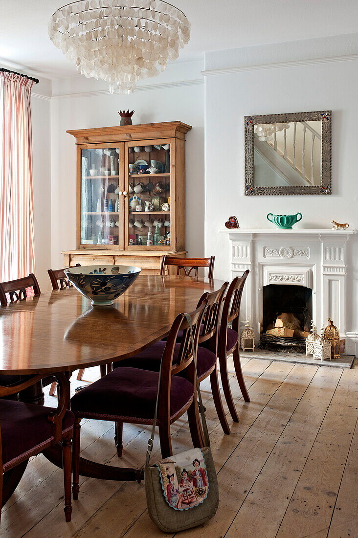 Wooden dining table and chairs with glass fronted dresser in Bovey Tracey family home, Devon, England, UK