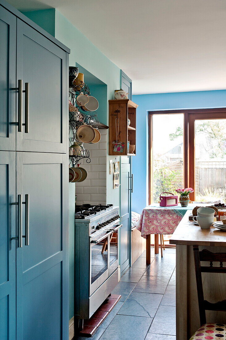 Crockery hanging above range oven in turquoise kitchen of Bovey Tracey family home, Devon, England, UK