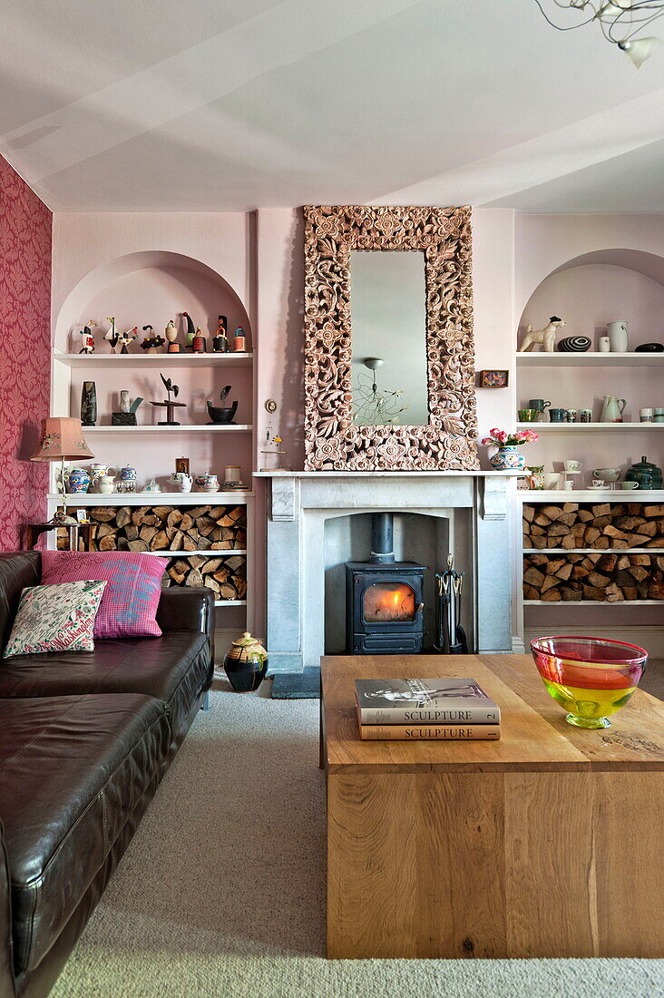 Schwarzes Ledersofa mit hölzernem Couchtisch in einem Wohnzimmer mit rosafarbenen Rundbögen in einem Familienhaus in Bovey Tracey, Devon, England, UK