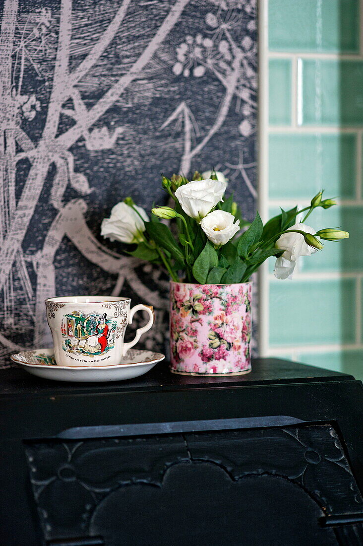 Cut flowers with vintage teacup in bathroom of Bovey Tracey family home, Devon, England, UK