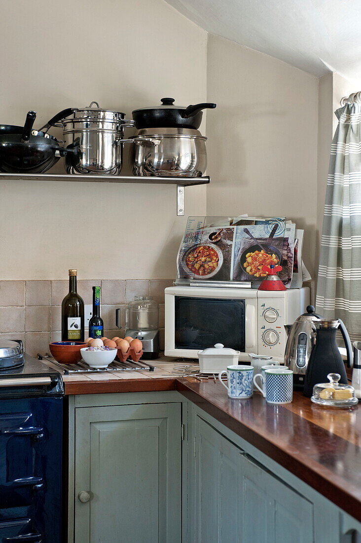 Mikrowelle und Wasserkocher mit Töpfen in einer Ecke der Küche eines Bauernhauses in Suffolk, England, Vereinigtes Königreich