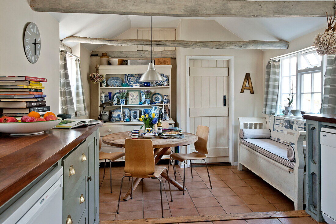 Circular wooden table and chairs with kitchen dresser in Suffolk farmhouse, England, UK