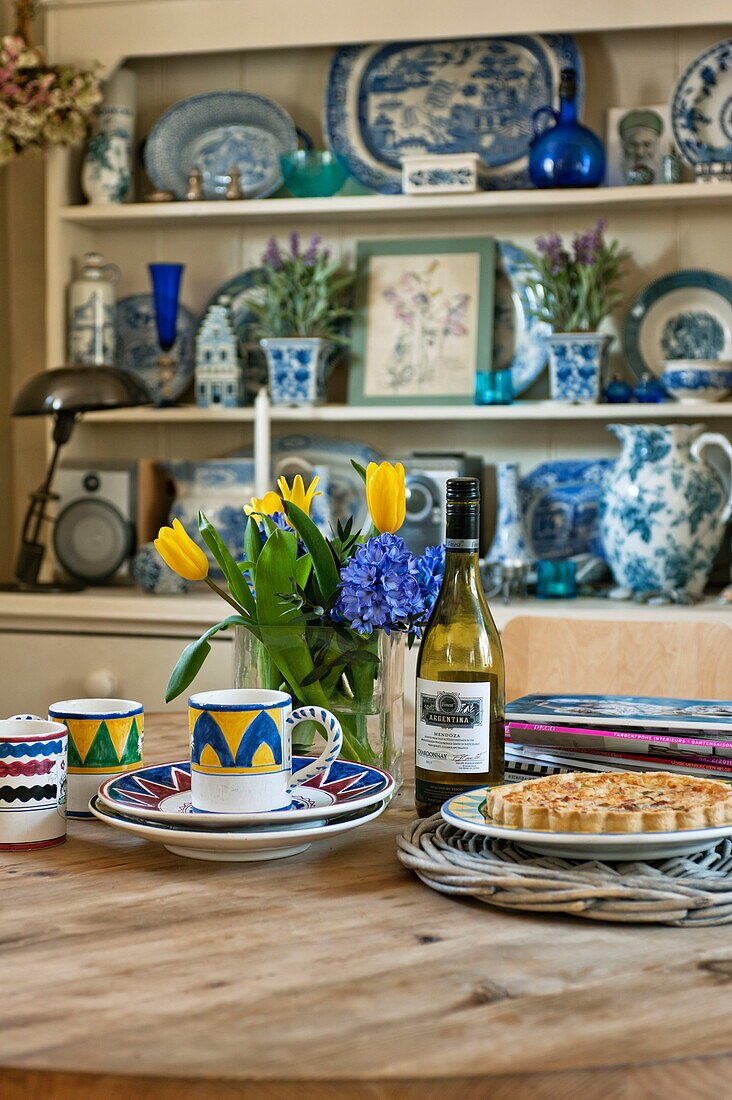 Blaue und weiße Keramik mit gelben Tulpen auf dem Küchentisch eines Bauernhauses in Suffolk, England, Vereinigtes Königreich