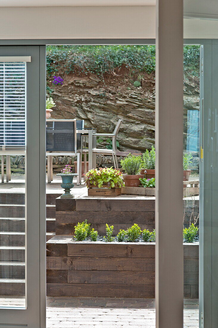 View through doorway to split level terrace with furniture and pot plants in Wadebridge, Cornwall, England, UK