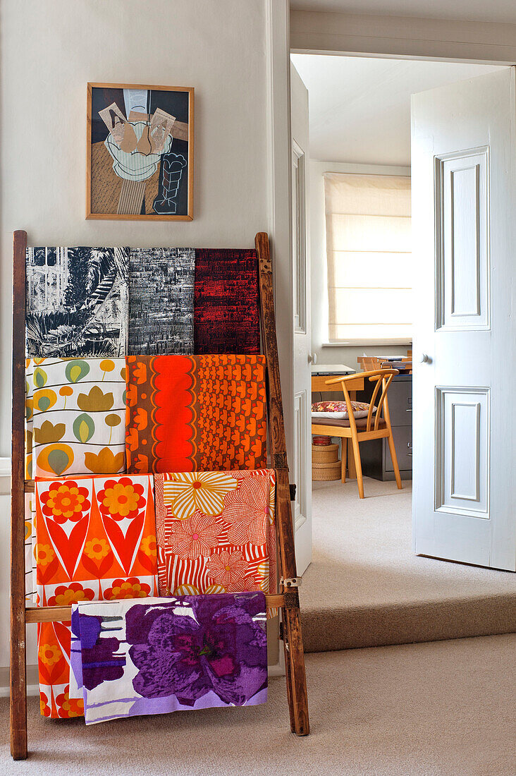 Bright fabric samples hang on rack in Hertfordshire home, England, UK