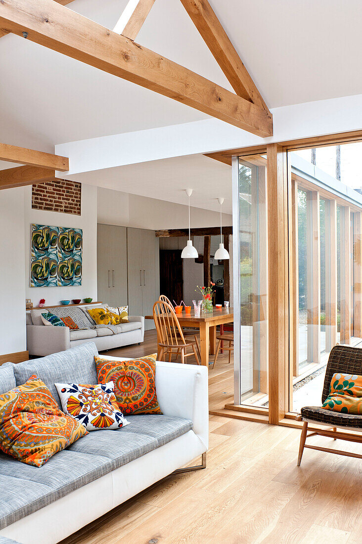 Retro styled cushions on grey sofa in open plan Hertfordshire family home, England, UK