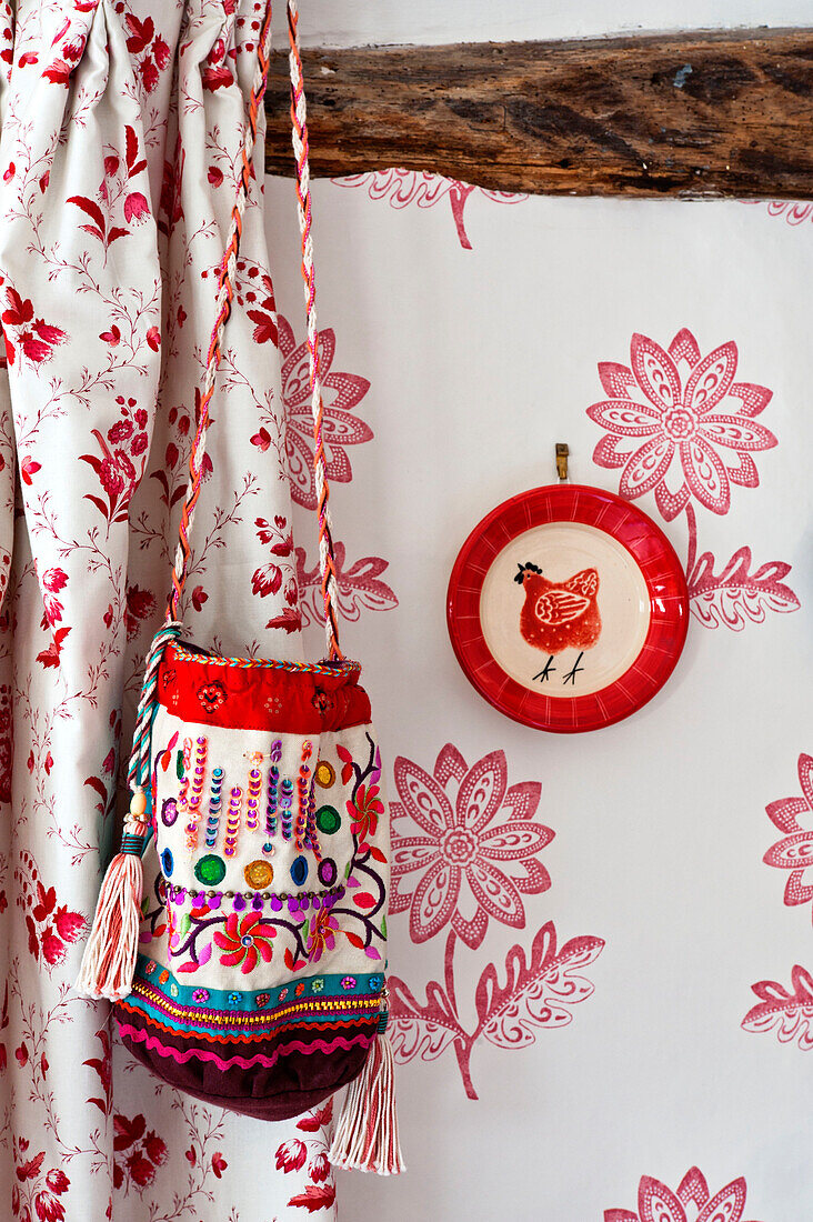 Bestickte Tasche mit Zierteller und gemusterter Tapete und Vorhang in einem Haus in Hertfordshire, England, Vereinigtes Königreich